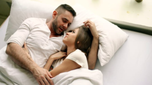 Esposo abrazando a su esposa en la cama y viendola con cariño