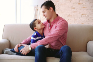 Hombre y su hijo abrazados en un sillon