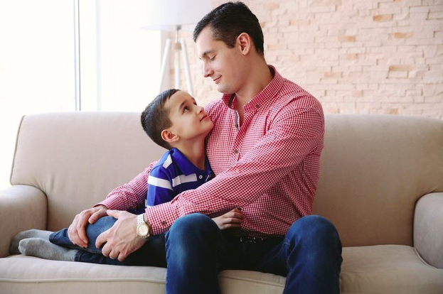 Hombre y su hijo abrazados en un sillon