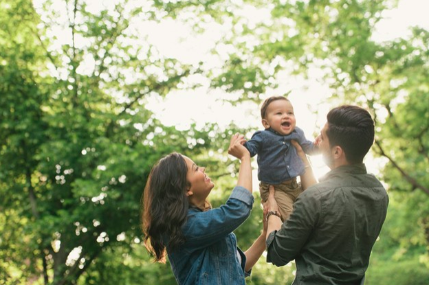 madre y padre jugando con su hijo en el bosque