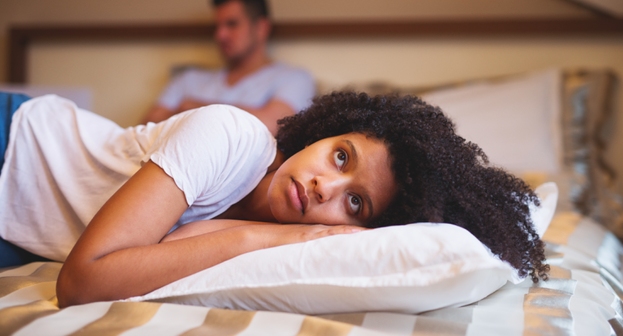 Mujer triste y su esposo al fondo