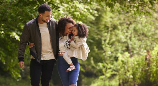 Padre y madre abrazando a su hija en el parque