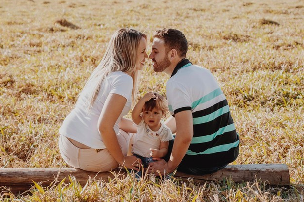 Padre y madre sentados en un tronco en el campo