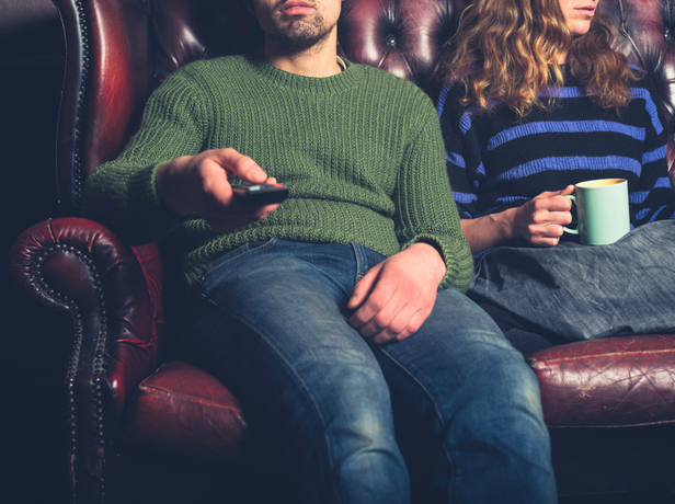 Esposo usando el control del televisor y su esposa viendo otro lado