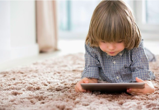 niño pequeño viendo una tablet en la sala