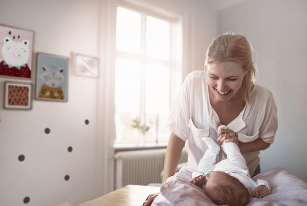 bebé siendo cambiado por su madre con una sonrisa