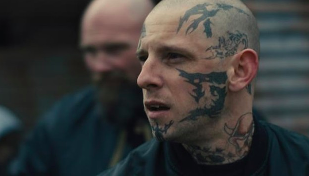 hombre con tatuajes en el rostro viendo algo