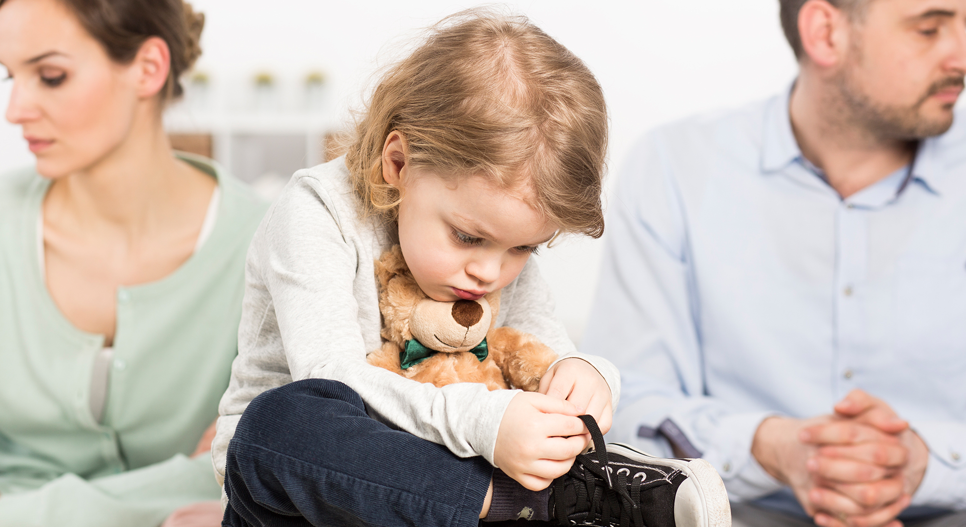 niña triste y sus padres enojados al fondo