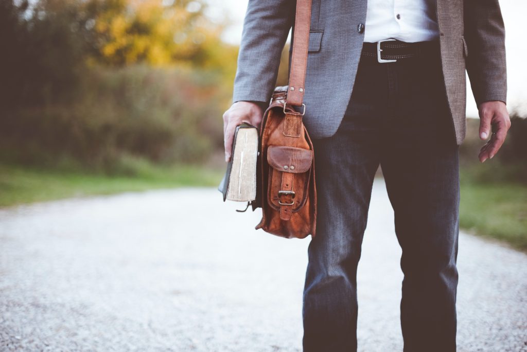 Hombre caminando por una calle con una biblia