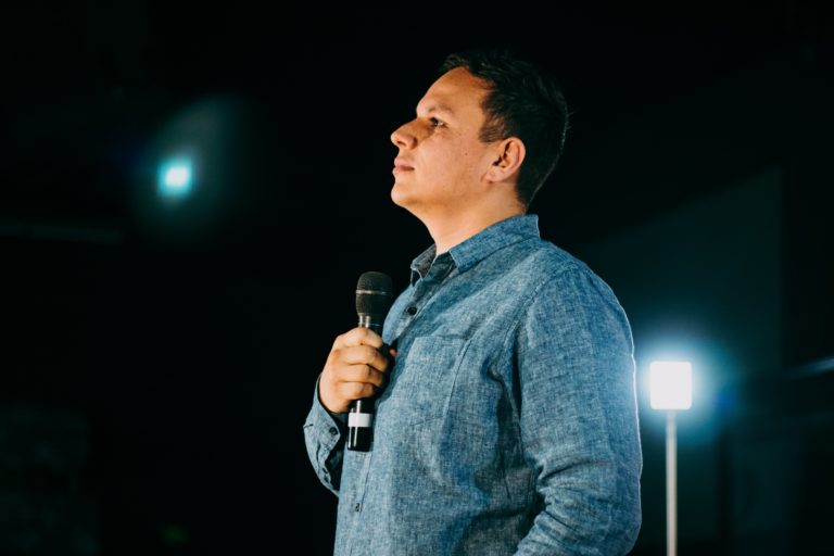 Pastor con un microfono en una tarima