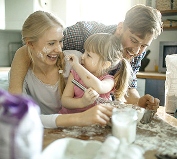 Niña jugando con pintura blanca con su mamá y papá