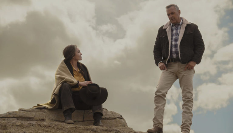 Una mujer sentada en una piedra junto a un hombre con sueta y algunas canas, escena de pelicula LET HIM GO