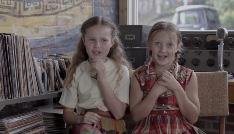 Niñas rubias sonriendo sentadas en lo que parece ser un estudio de radio,Escena de la pelicula AMORE DE CALENDARIO
