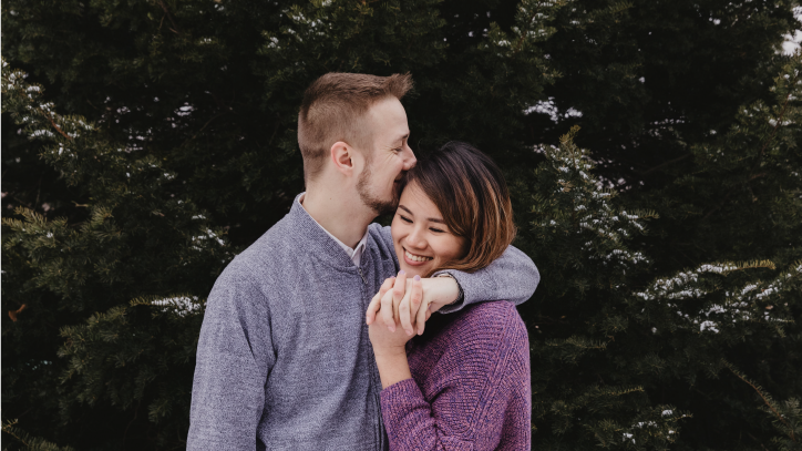 Pareja de novios debajo de un pino abrazados sonriendo