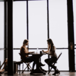 Persona con computadora frente a mujer escribiendo en una consejería coaching