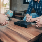 Personas siendo aconsejadas teniendo la biblia en el centro de la mesa
