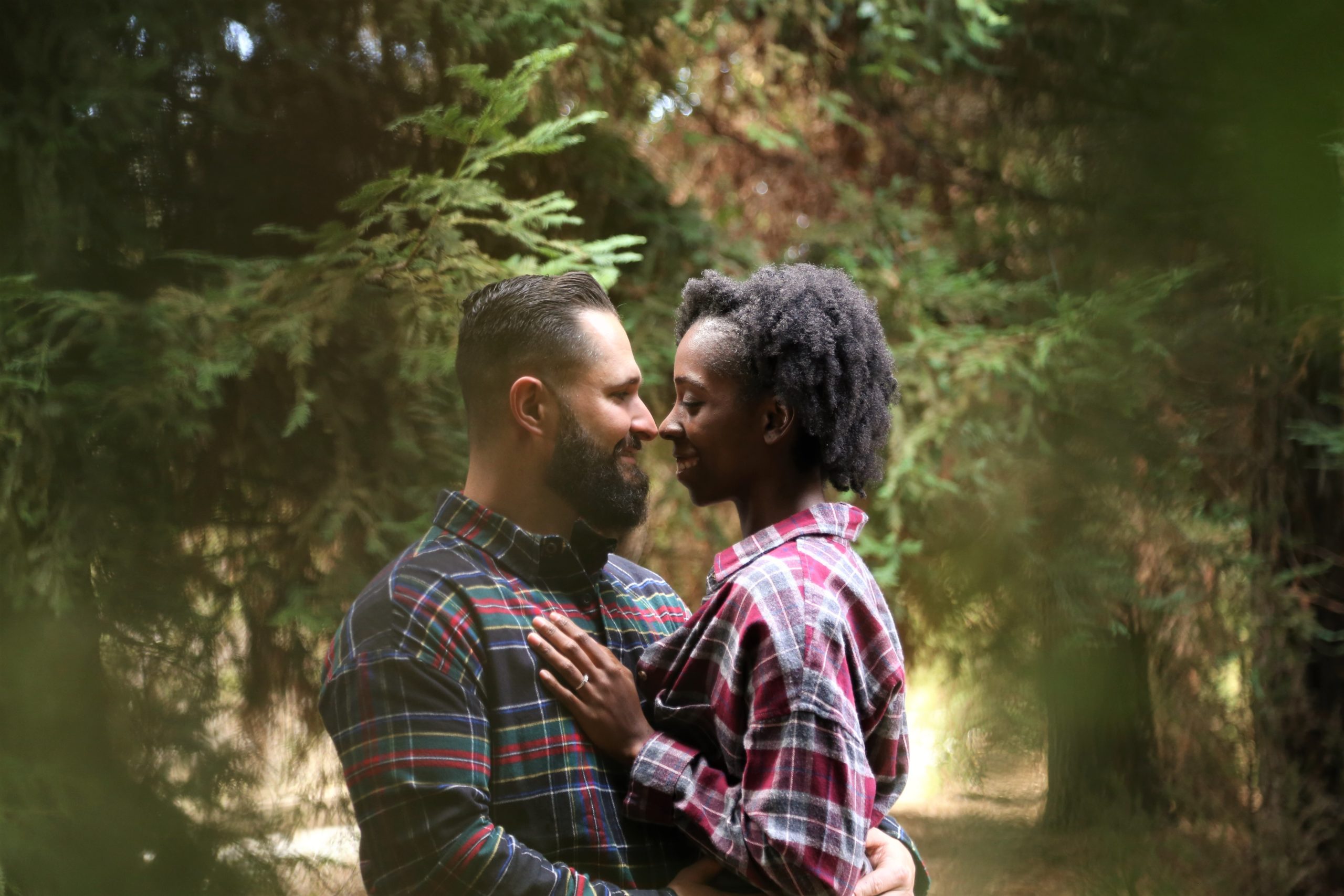 Pareja abrazados mirandose uno al otro en un bosque alegres