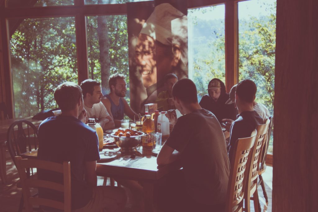 Jovenes en una cabaña en el bosque comiendo